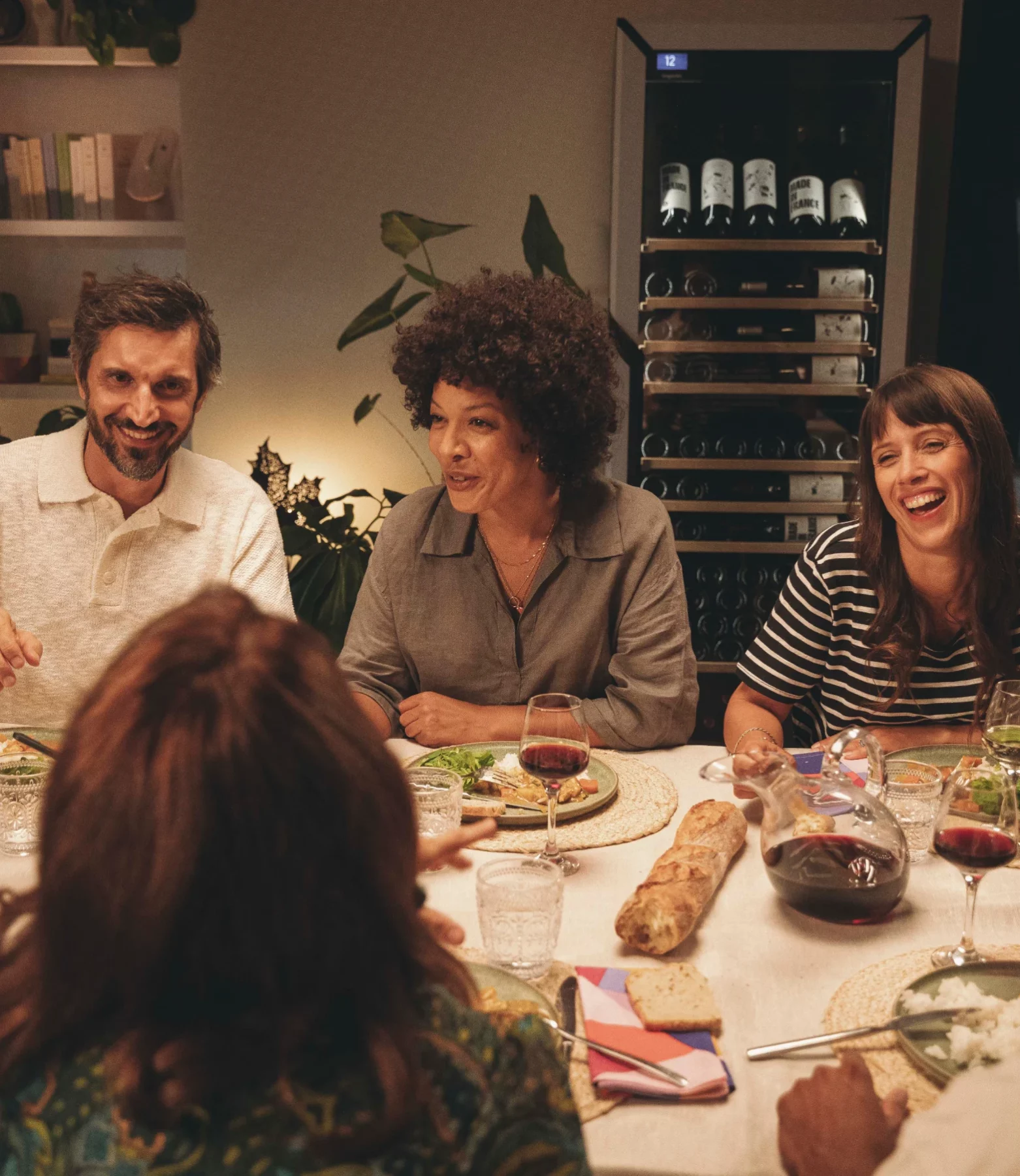 Friends sharing wine at dinner beside a Goguette wine fridge